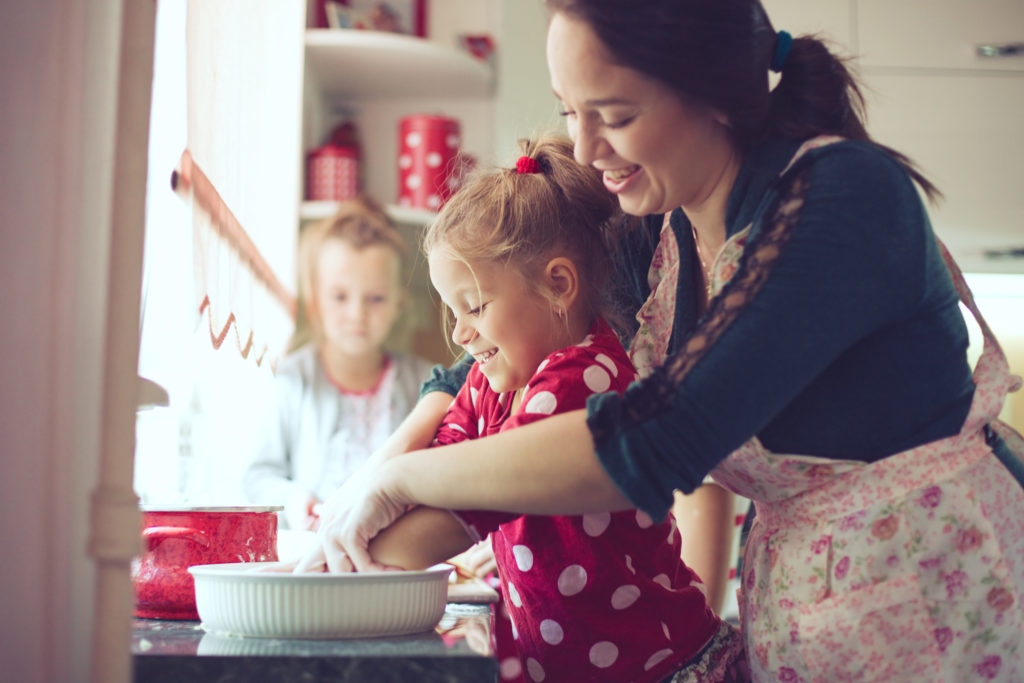 Mother with her 5 years old kids cooking holiday pie in the kitchen, casual lifestyle photo series in real life interior