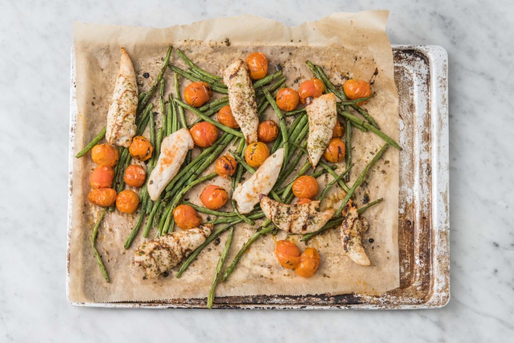 Roasted chicken, tomatoes, and green beans baked on a sheet pan