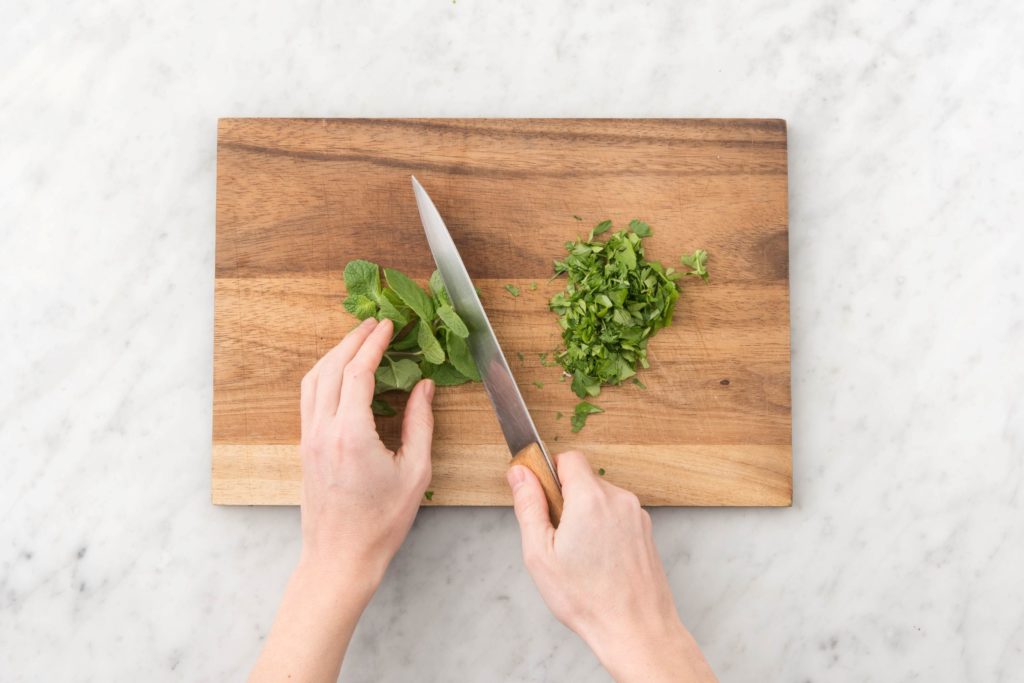 Person chopping fresh herbs on a cutting board